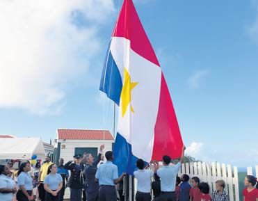 Island Governor Jonathan Johnson, assisted by students, hoisting the flag for Saba Day 2016.